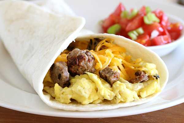Hot and delicious breakfast burrito with cheese, eggs, and sausage in a tortilla